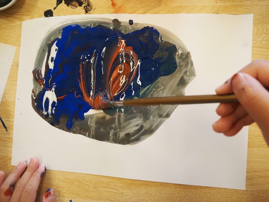 絵の具を重ねて色の変化を確かめる子どもの様子